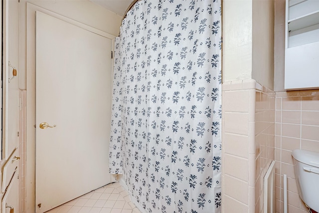 bathroom with toilet, tile patterned flooring, tile walls, and a shower with shower curtain