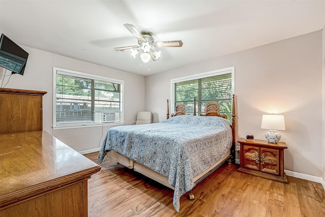 bedroom featuring light wood-type flooring, multiple windows, baseboards, and a ceiling fan