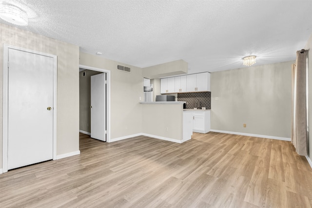 unfurnished living room featuring a textured ceiling and light hardwood / wood-style flooring