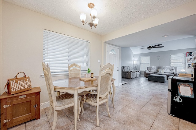 dining area featuring a textured ceiling, ceiling fan with notable chandelier, and light tile patterned floors