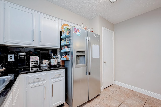 kitchen featuring white cabinets, light tile patterned floors, stainless steel refrigerator with ice dispenser, and a textured ceiling