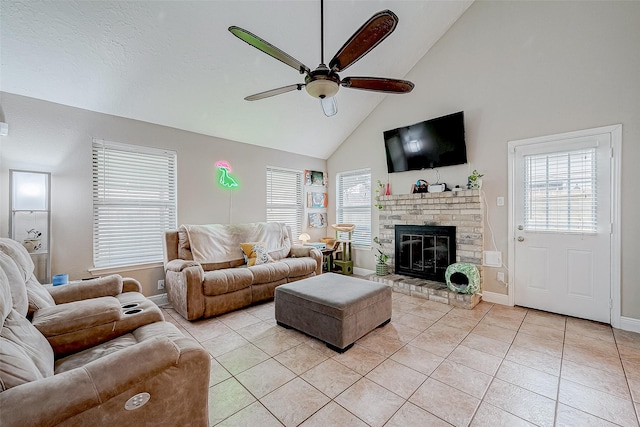 living room with ceiling fan, a fireplace, light tile patterned floors, and high vaulted ceiling