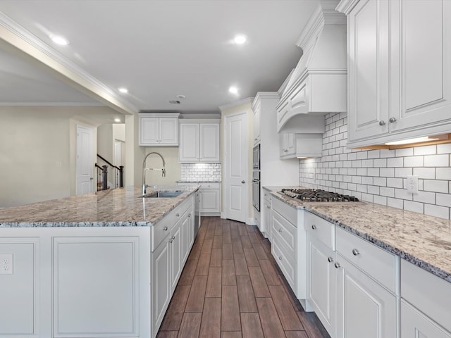 kitchen featuring light stone counters, sink, white cabinetry, and a kitchen island with sink