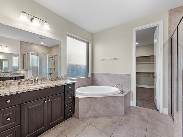 bathroom featuring plus walk in shower, vanity, and tile patterned flooring