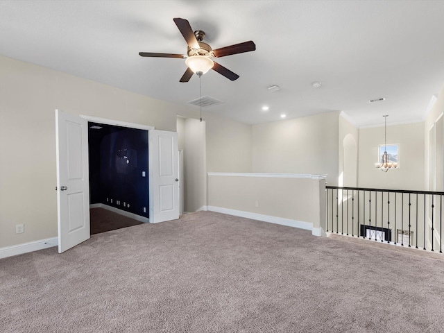 carpeted spare room featuring ceiling fan with notable chandelier