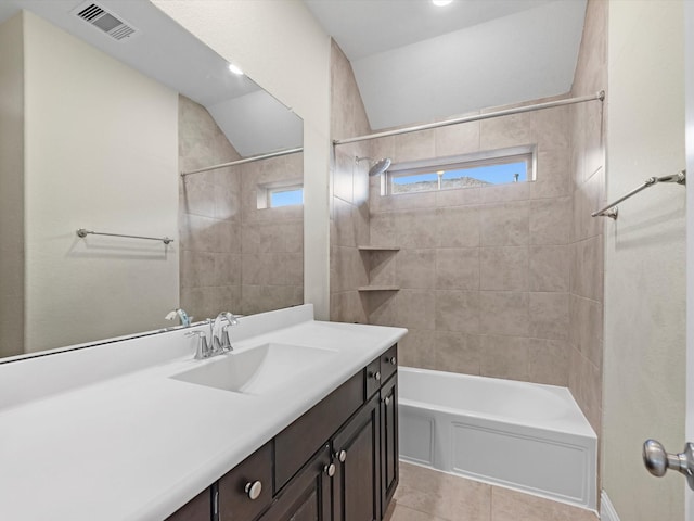 bathroom featuring tile patterned flooring, tiled shower / bath combo, and vanity