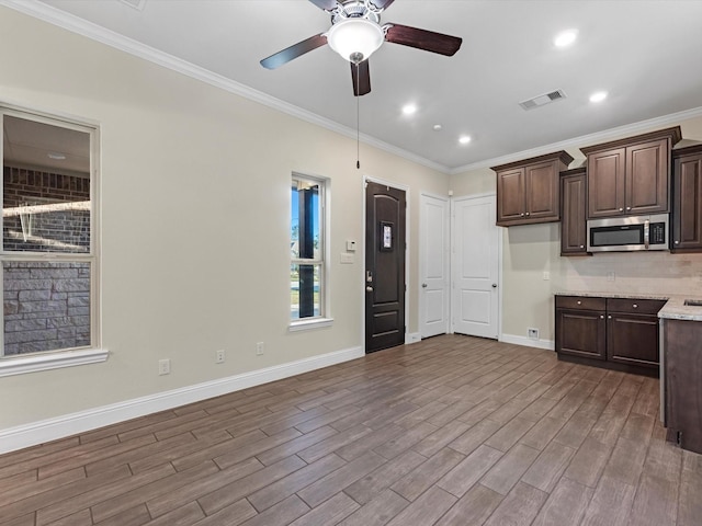 kitchen with light stone countertops, ceiling fan, dark brown cabinetry, and ornamental molding