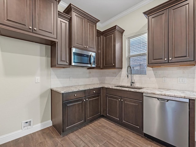 kitchen with hardwood / wood-style floors, sink, ornamental molding, dark brown cabinetry, and stainless steel appliances