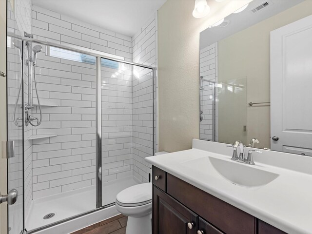 bathroom featuring vanity, toilet, and a shower with shower door