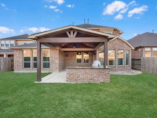 back of property featuring a lawn, ceiling fan, area for grilling, and a patio area