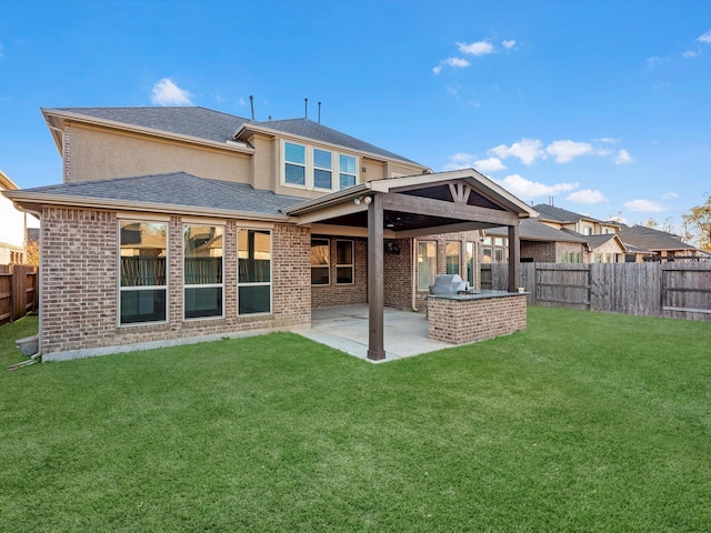 rear view of house with a lawn, an outdoor kitchen, and a patio area