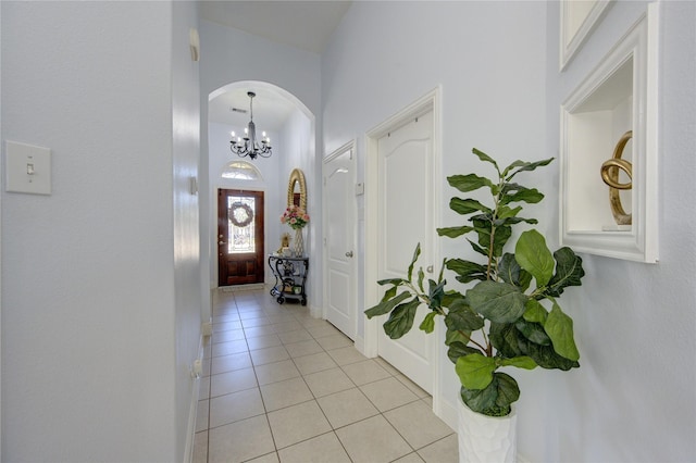 foyer entrance with a towering ceiling, light tile patterned floors, and an inviting chandelier