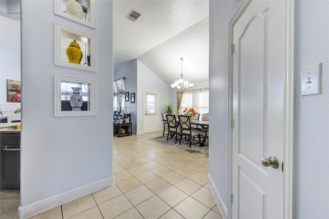 hallway featuring light tile patterned floors, lofted ceiling, and a notable chandelier