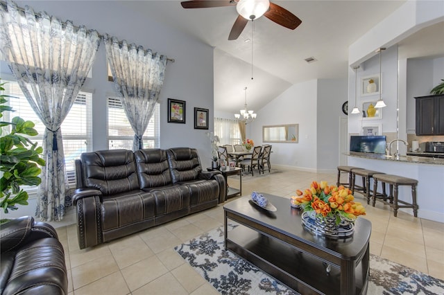 tiled living room featuring vaulted ceiling, a healthy amount of sunlight, and ceiling fan with notable chandelier