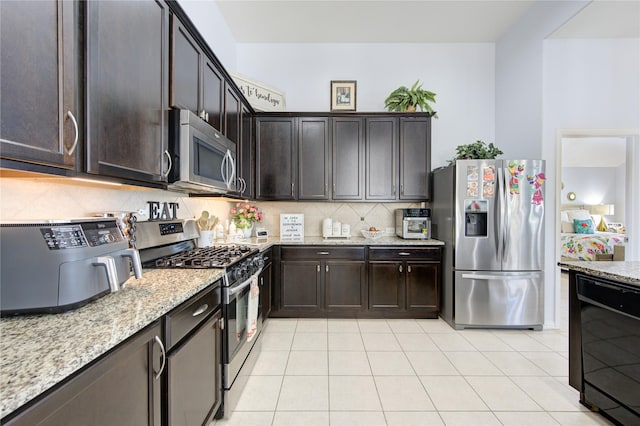 kitchen with light stone countertops, light tile patterned floors, dark brown cabinetry, and stainless steel appliances