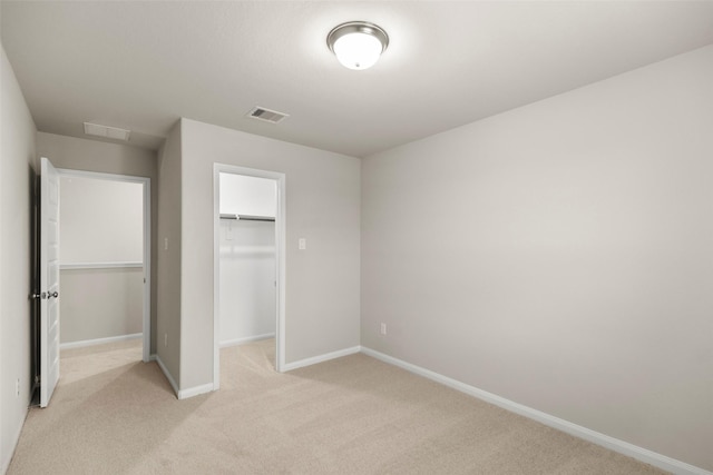 unfurnished bedroom with a spacious closet, a closet, and light carpet