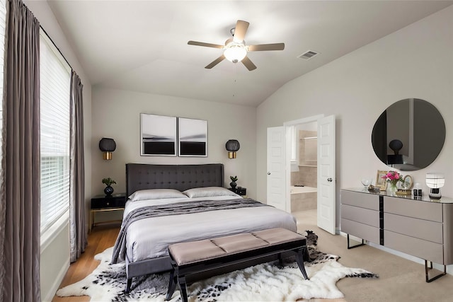 bedroom featuring ensuite bath, ceiling fan, vaulted ceiling, and light wood-type flooring