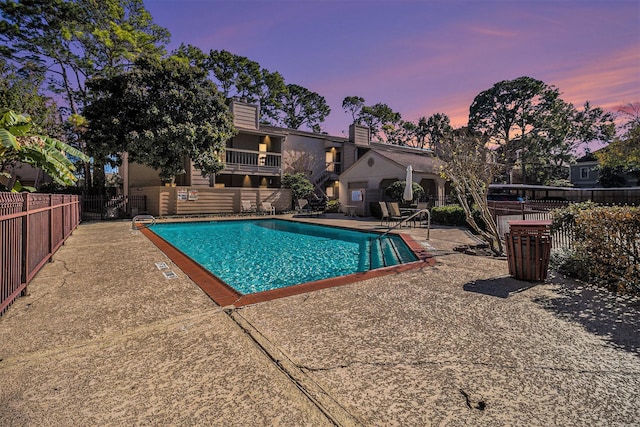 pool at dusk with a patio area