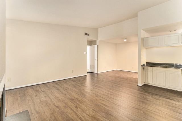 unfurnished living room featuring hardwood / wood-style flooring and vaulted ceiling