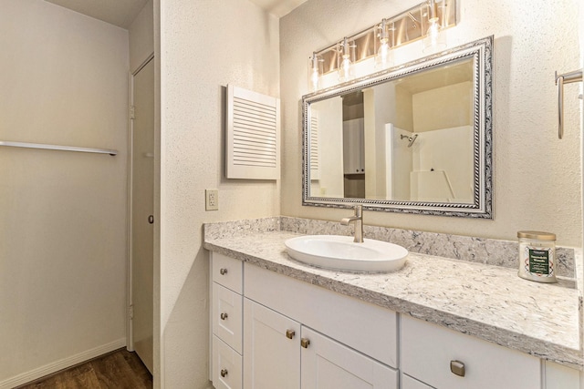 bathroom featuring hardwood / wood-style floors, vanity, and walk in shower