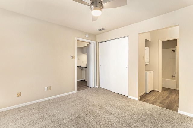 unfurnished bedroom featuring carpet, connected bathroom, ceiling fan, and stacked washer and clothes dryer