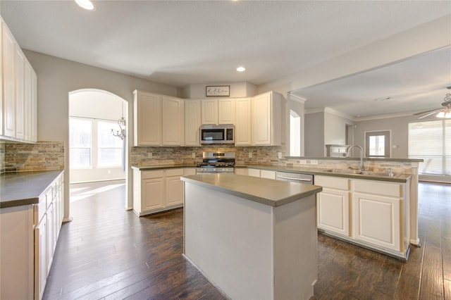 kitchen featuring white cabinets, sink, a kitchen island, kitchen peninsula, and stainless steel appliances