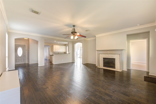 unfurnished living room with ceiling fan, dark wood-type flooring, and ornamental molding