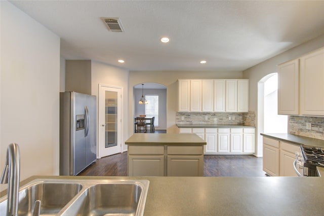 kitchen with a center island, sink, decorative backsplash, appliances with stainless steel finishes, and dark hardwood / wood-style flooring