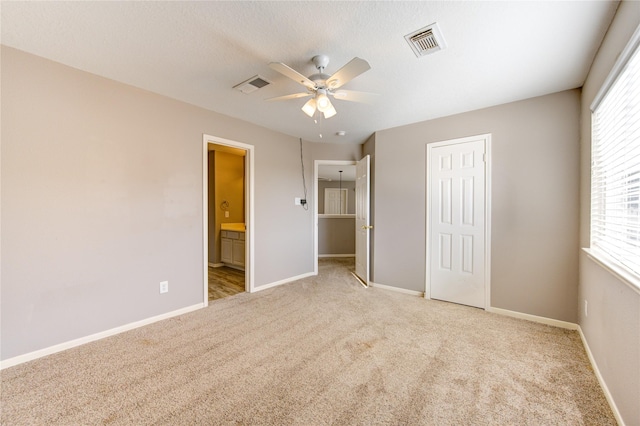 unfurnished bedroom with light carpet, a closet, ensuite bath, and ceiling fan