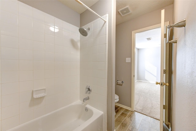 bathroom featuring tiled shower / bath and toilet