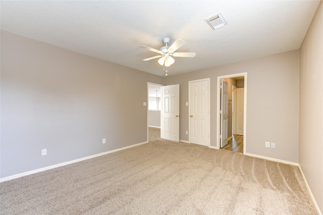 unfurnished bedroom featuring ceiling fan, light colored carpet, and a textured ceiling