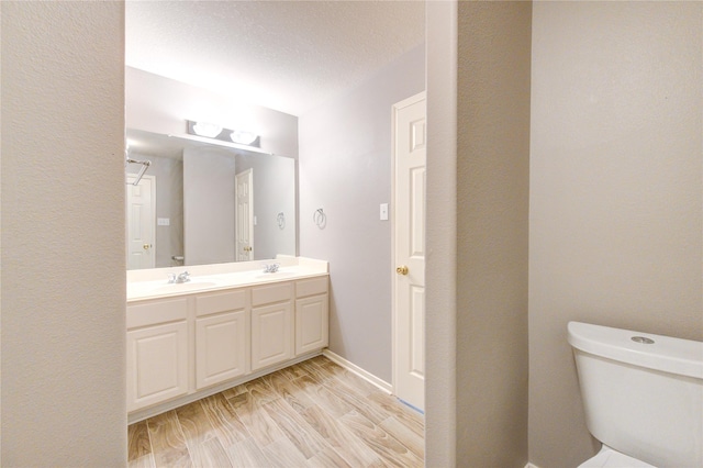 bathroom with vanity, a textured ceiling, hardwood / wood-style flooring, and toilet