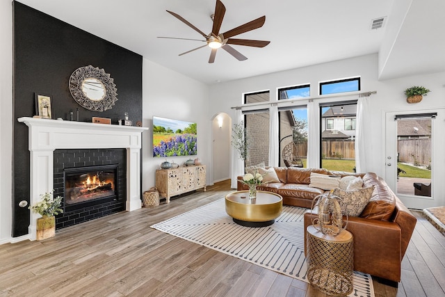 living room featuring ceiling fan, light hardwood / wood-style floors, and a fireplace