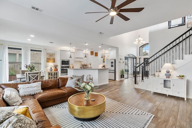 living room with light hardwood / wood-style floors and ceiling fan with notable chandelier