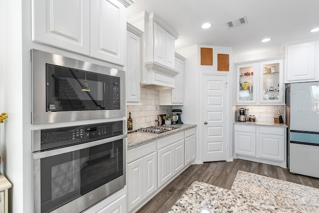 kitchen featuring tasteful backsplash, built in microwave, stainless steel gas cooktop, white refrigerator, and white cabinetry