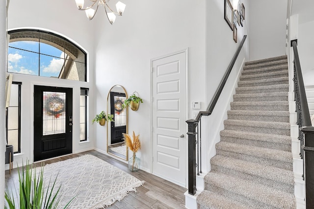 entryway with hardwood / wood-style floors, an inviting chandelier, and a high ceiling