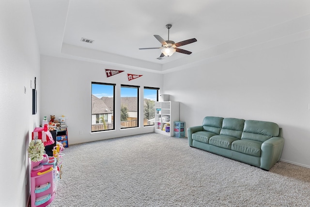 playroom featuring carpet floors, a tray ceiling, and ceiling fan