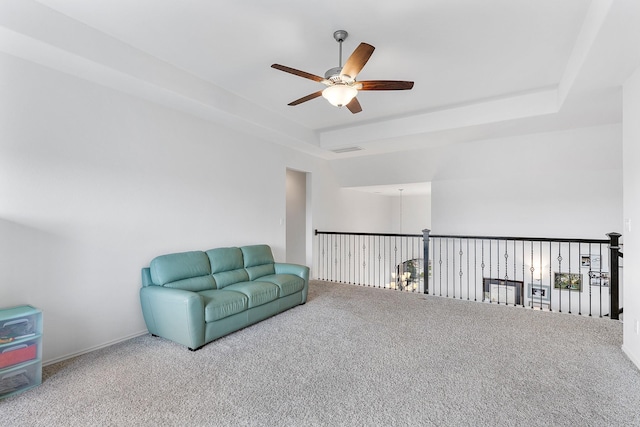 sitting room featuring carpet flooring, a tray ceiling, and ceiling fan