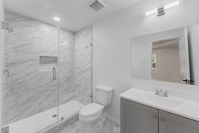 bathroom featuring a shower with door, vanity, and toilet