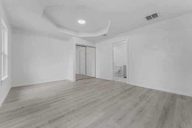 unfurnished room featuring a raised ceiling and light hardwood / wood-style flooring