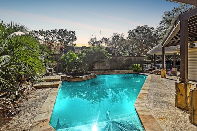 pool at dusk with a patio area