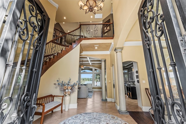 tiled foyer entrance with ceiling fan, ornamental molding, and ornate columns