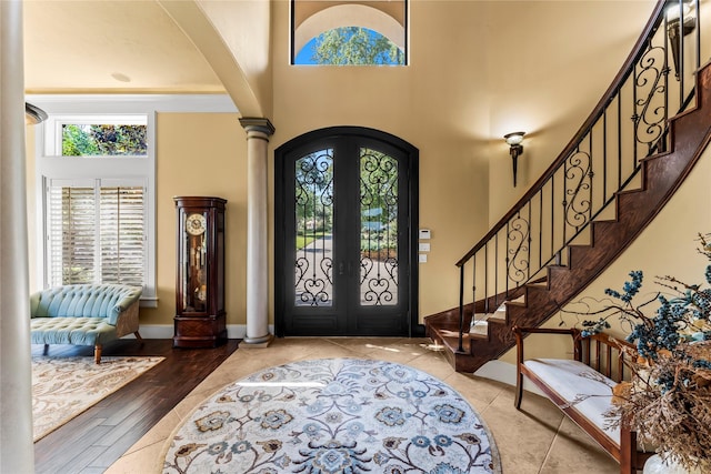 foyer entrance with hardwood / wood-style flooring, decorative columns, french doors, and a high ceiling