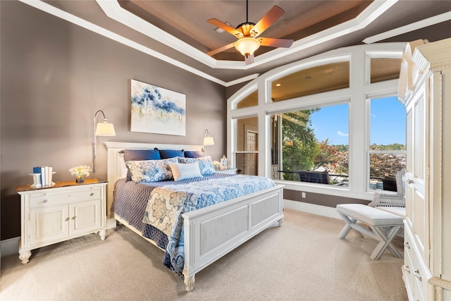 carpeted bedroom featuring ceiling fan, ornamental molding, and a tray ceiling