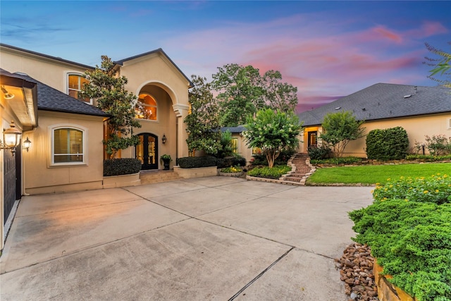 view of front of property with a patio, a lawn, and french doors