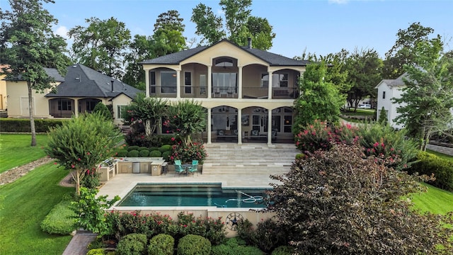 back of house with a patio area, a balcony, and a lawn