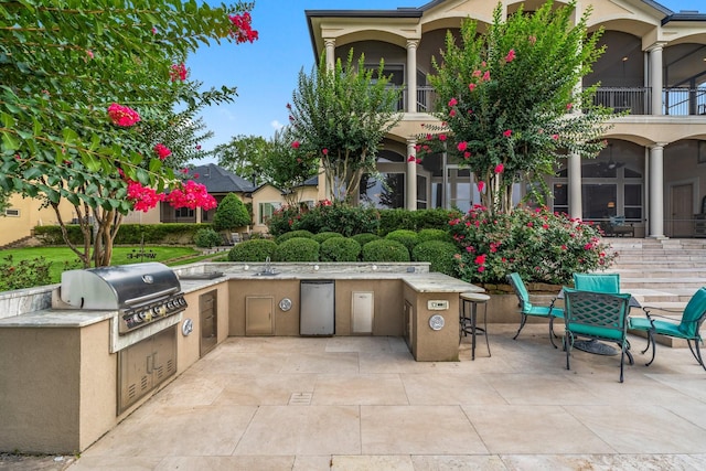 view of patio / terrace featuring a balcony, a grill, and exterior kitchen