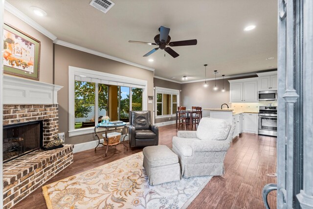 living room featuring dark hardwood / wood-style flooring, a brick fireplace, and ornamental molding