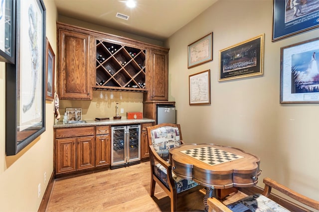 bar with wine cooler and light wood-type flooring