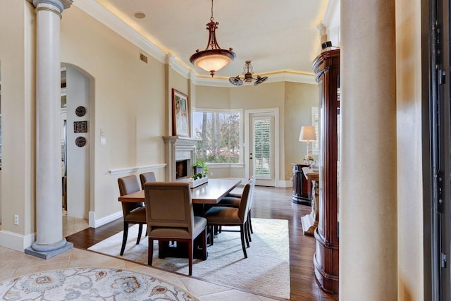 tiled dining room with decorative columns and ornamental molding